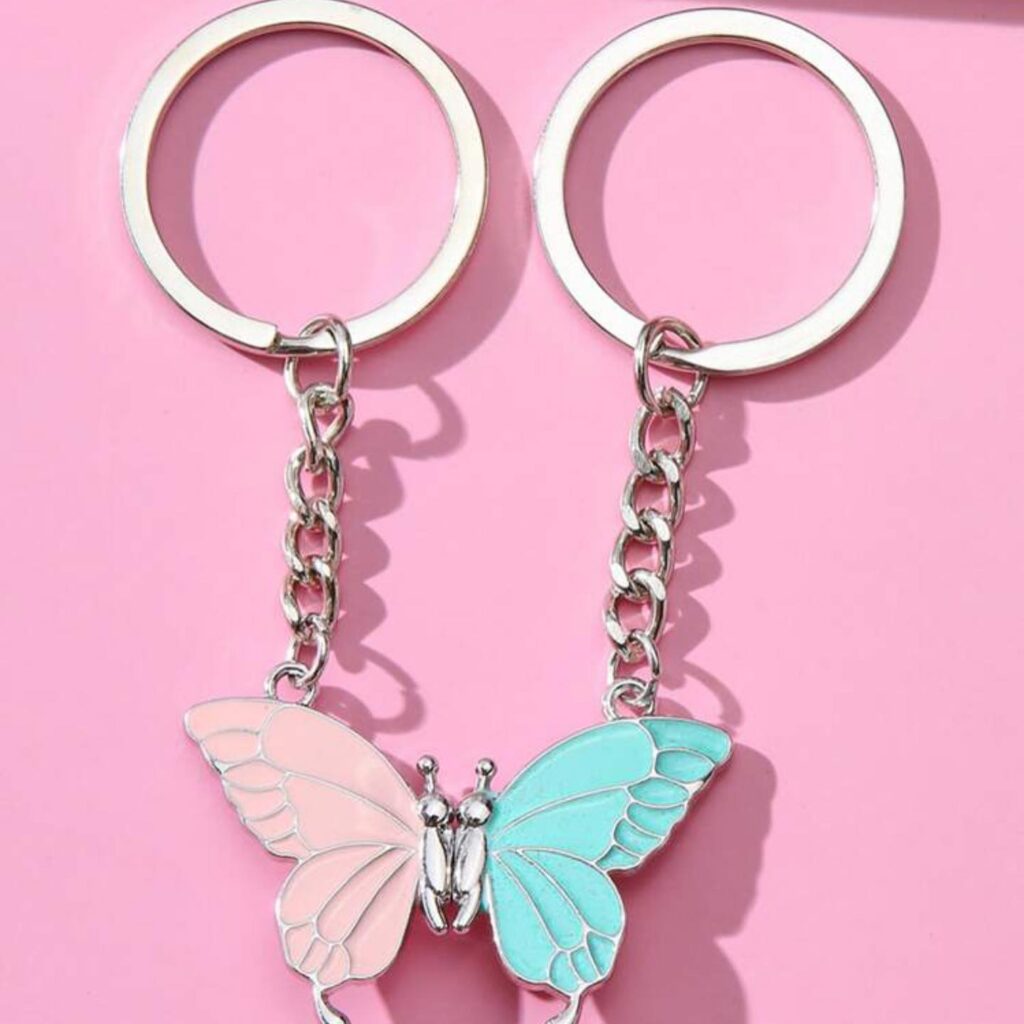 Pastel-colored butterfly keychains in pink and blue, presented on a pink background.
