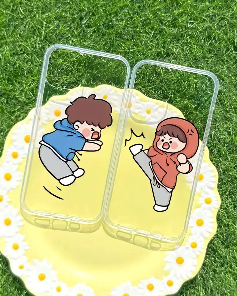 Two yellow iPhone cases with cartoon characters in a playful chase, set against a grassy background with floral accents.