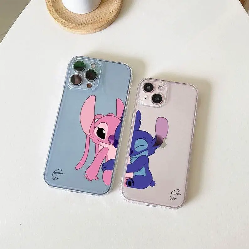 Two iPhone cases, one blue and one pink, each featuring a cartoon character in an embrace, set against a white wooden background.