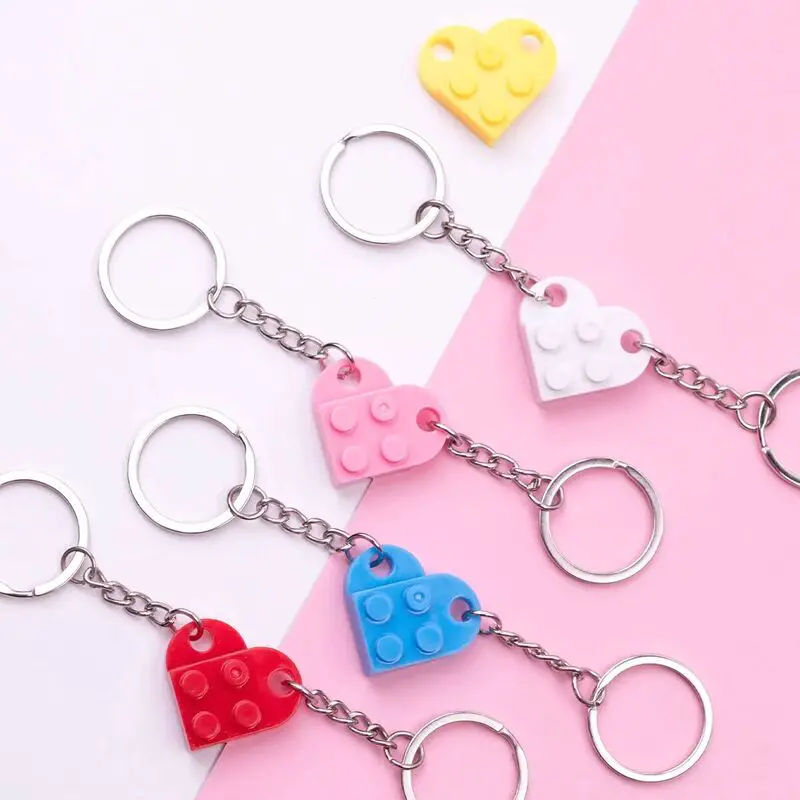 A collection of Lego-style heart keychains in various colors, displayed against a pink background.