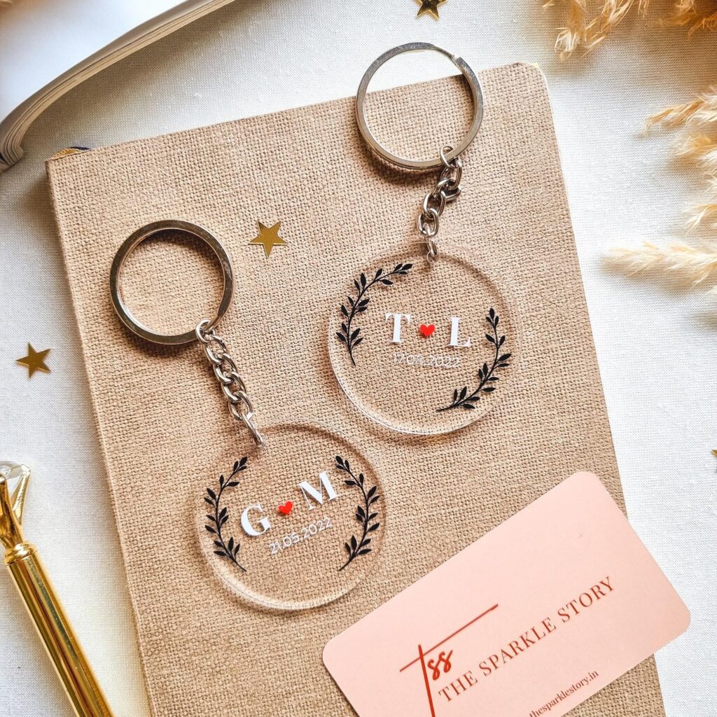 Clear acrylic circle keychains with black wreath designs and personalized initials and dates.