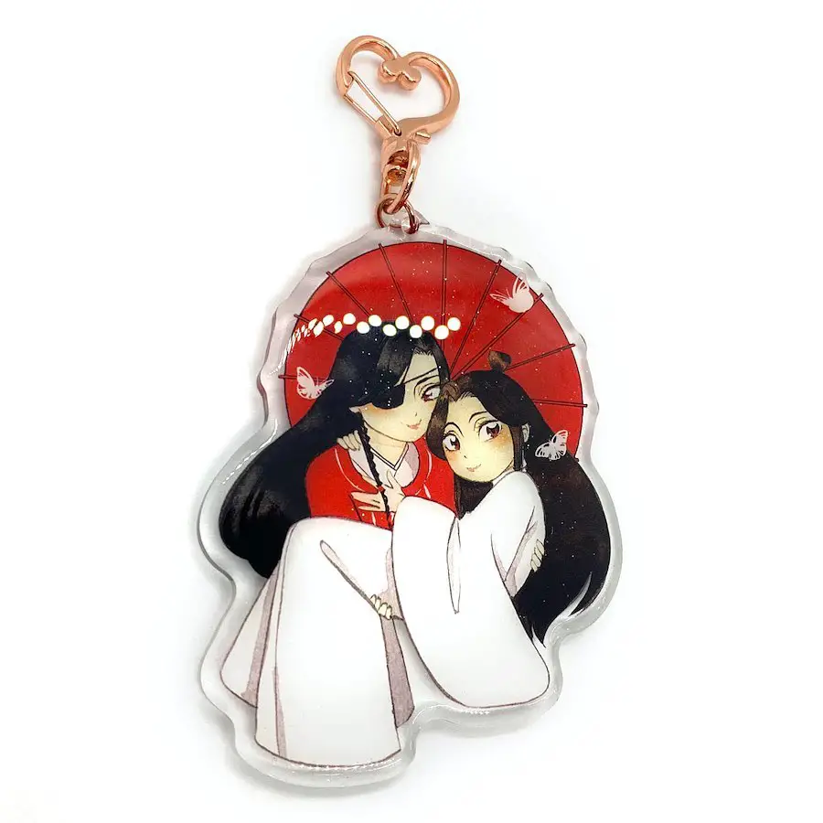 A keychain depicting an anime couple under a red umbrella, detailed with traditional attire and butterfly motifs.