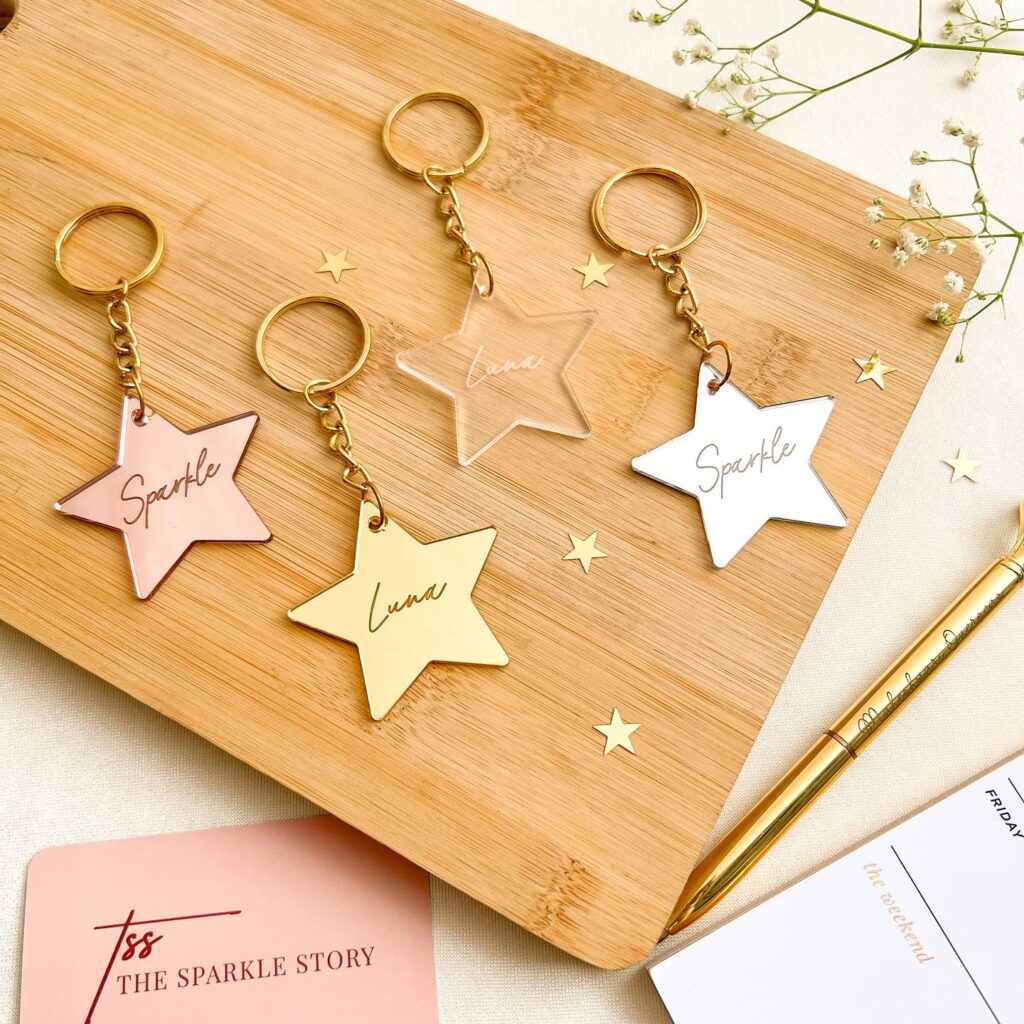 Star-shaped acrylic keychains with names and inspirational words, presented on a wooden background.