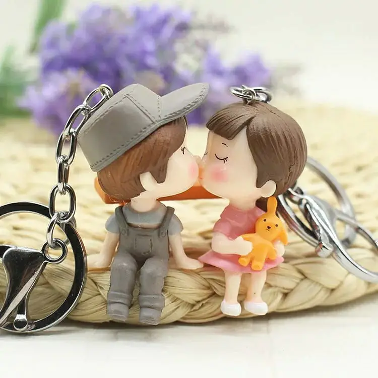 Two keychains depicting a couple in cowboy attire kissing, complete with detailed hats and playful accessories.