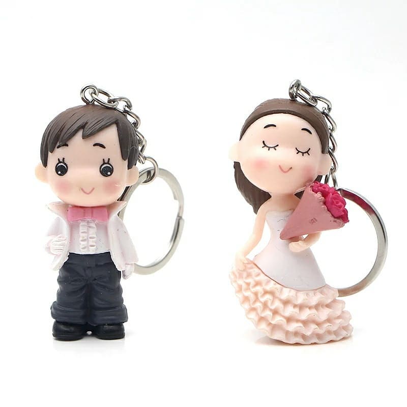 Cartoon keychains of a bride in a white dress holding a bouquet and a groom in a tuxedo, ideal for wedding favors.